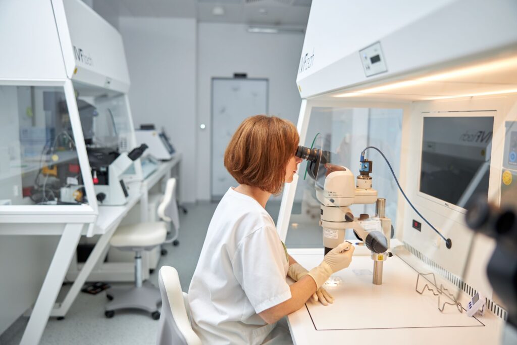 Moderné embryologické laboratórium IVF centra s embryologičkou pozerajúcou do mikroskopu