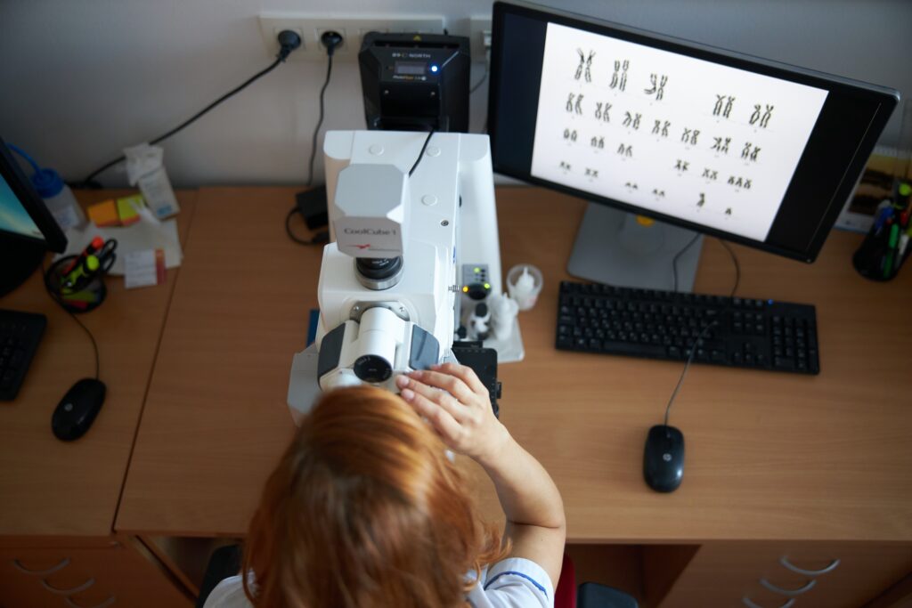 lekárka genetička skúmajúca chromozómy cez špeciálny mikroskop. Karyoptyp.